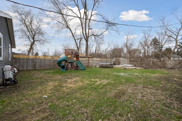 view of yard with a trampoline, a fenced backyard, and a playground