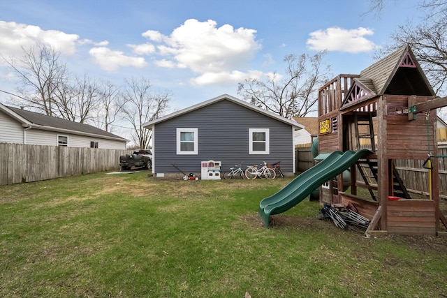 rear view of property featuring a yard, a fenced backyard, and a playground