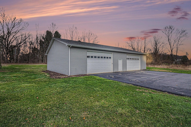 garage at dusk featuring a yard and a detached garage