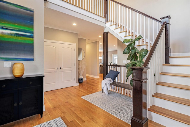 staircase featuring baseboards, ornamental molding, recessed lighting, a high ceiling, and wood finished floors