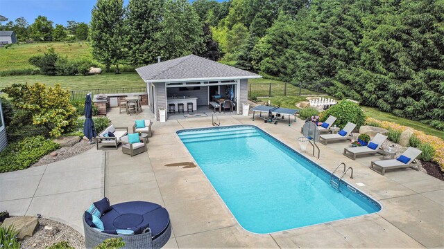 view of swimming pool featuring an outbuilding, fence, a patio, and a storage structure