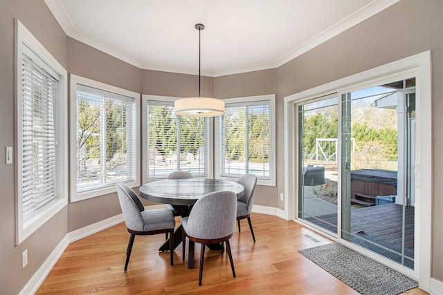 dining room featuring crown molding, baseboards, and light wood finished floors