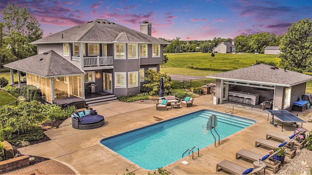 outdoor pool featuring an outdoor living space with a fire pit, an outbuilding, a lawn, grilling area, and a patio area