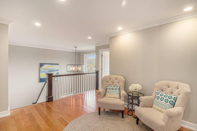 sitting room featuring baseboards, an inviting chandelier, ornamental molding, an upstairs landing, and wood finished floors