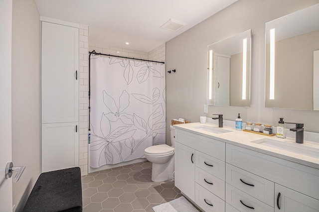 full bath featuring toilet, double vanity, a sink, and tile patterned flooring