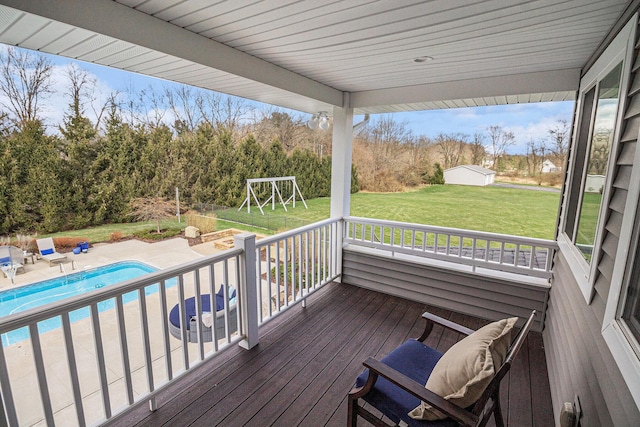wooden deck featuring an outdoor pool, a patio area, an outdoor structure, and a lawn