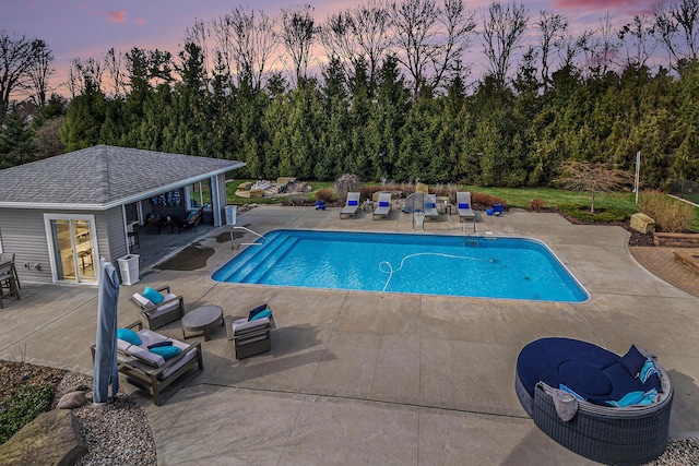pool at dusk featuring central AC, an exterior structure, an outdoor pool, a patio, and an outbuilding