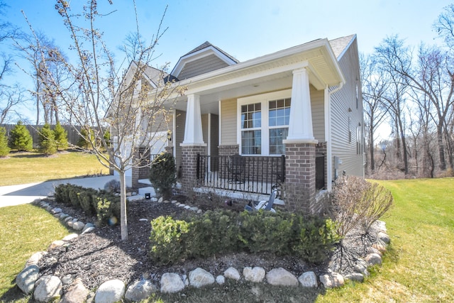 view of front of property featuring a porch, brick siding, and a front yard