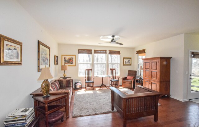 living room featuring ceiling fan, baseboards, and hardwood / wood-style floors
