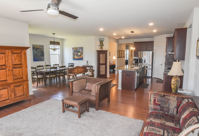 living room featuring recessed lighting, ceiling fan with notable chandelier, and dark wood finished floors