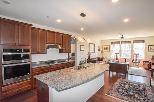 kitchen featuring gas stovetop, a sink, open floor plan, double oven, and under cabinet range hood