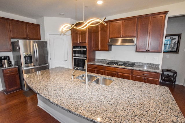 kitchen featuring a sink, dark wood-type flooring, under cabinet range hood, appliances with stainless steel finishes, and light stone counters