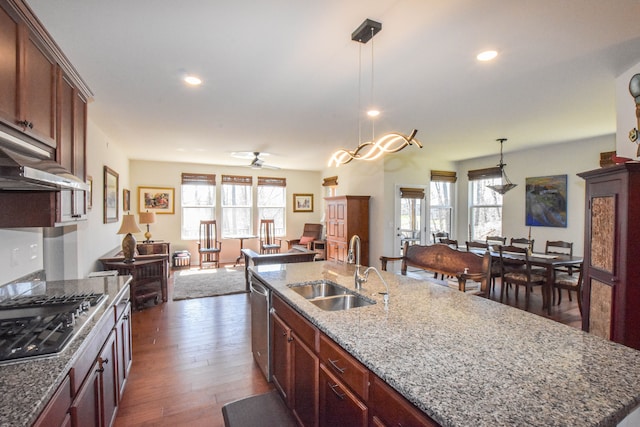 kitchen featuring a sink, open floor plan, a kitchen island with sink, dark wood-style flooring, and appliances with stainless steel finishes