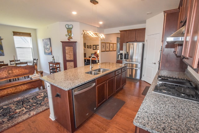 kitchen featuring light stone countertops, a sink, dark wood-type flooring, a kitchen island with sink, and appliances with stainless steel finishes