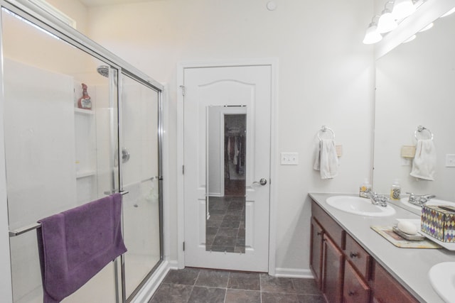 bathroom with a sink, double vanity, a stall shower, and baseboards