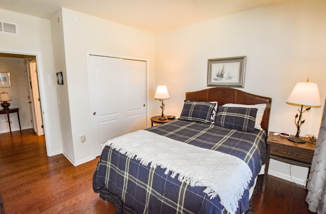 bedroom featuring baseboards, a closet, visible vents, and wood finished floors