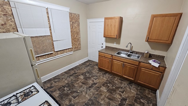 4107 N Campbell St, Detroit, MI 48210 - kitchen featuring baseboards, freestanding refrigerator, dark countertops, stone finish flooring, and a sink