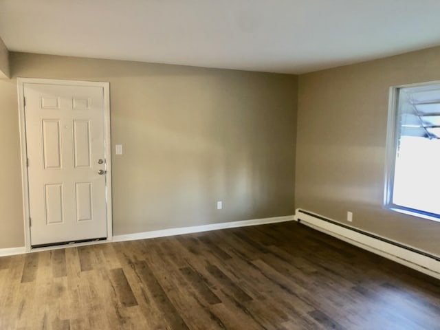 spare room featuring baseboard heating, baseboards, and wood finished floors