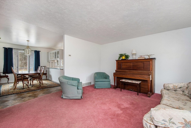 sitting room featuring a textured ceiling, baseboards, visible vents, and carpet floors