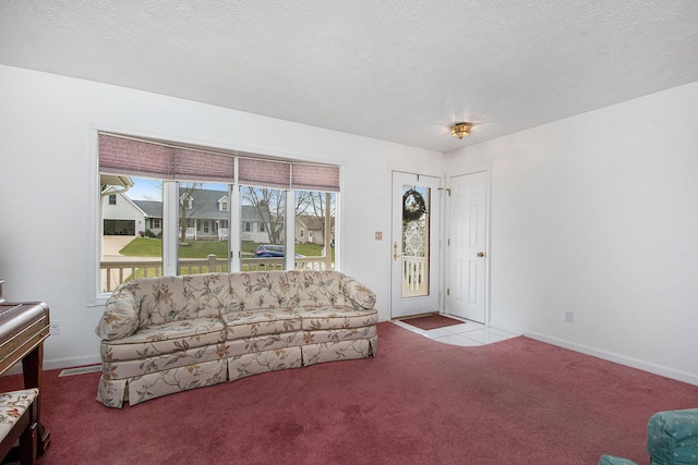 living area featuring visible vents, carpet flooring, and a textured ceiling