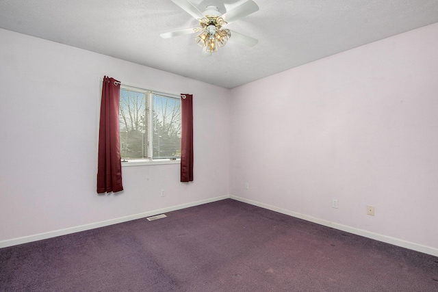 empty room featuring dark carpet, baseboards, a ceiling fan, and visible vents
