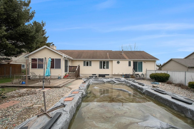 rear view of property featuring a deck, a chimney, and fence