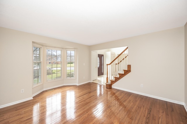 5521 Lohr Lake Dr, Ann Arbor, MI 48108 - unfurnished room featuring baseboards, wood finished floors, and stairway