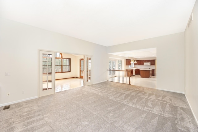 5521 Lohr Lake Dr, Ann Arbor, MI 48108 - unfurnished living room featuring french doors, light carpet, and baseboards