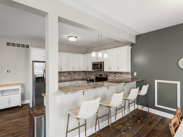 kitchen with stainless steel appliances, light stone counters, visible vents, decorative backsplash, and white cabinets