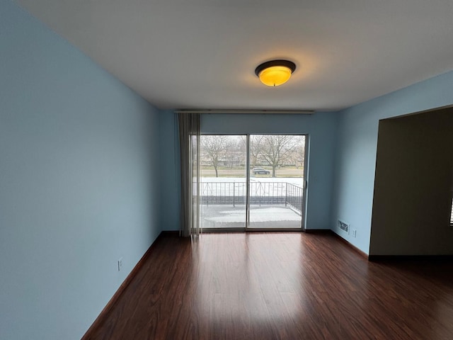 spare room with baseboards, dark wood-style flooring, and visible vents