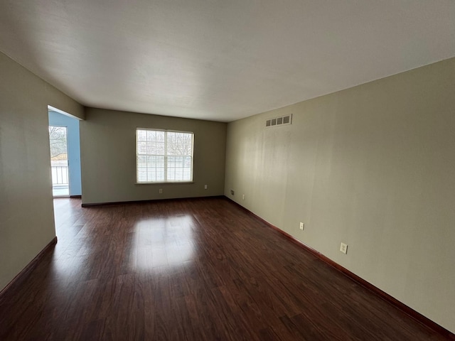 spare room featuring visible vents, dark wood finished floors, and baseboards