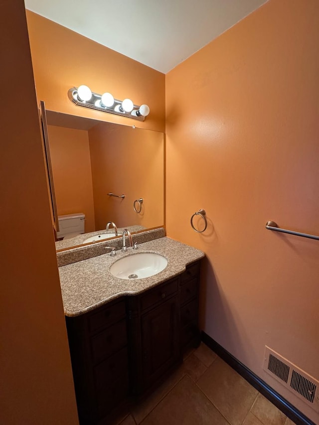 half bathroom featuring visible vents, tile patterned flooring, vanity, baseboards, and toilet