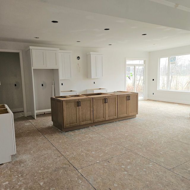 kitchen with a center island, baseboards, and white cabinets
