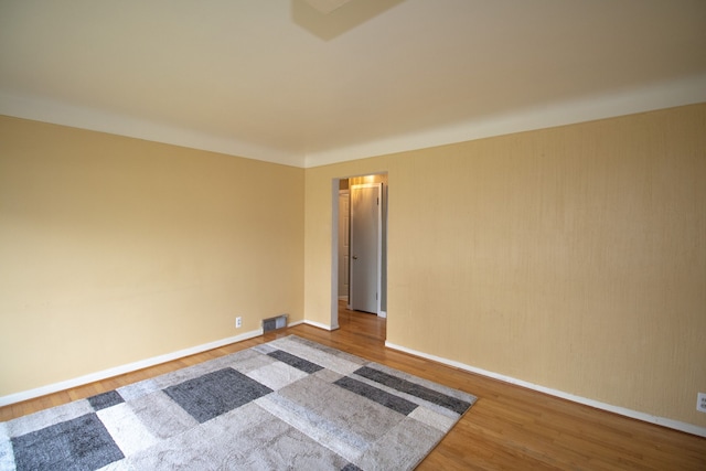 empty room featuring visible vents, baseboards, and wood finished floors