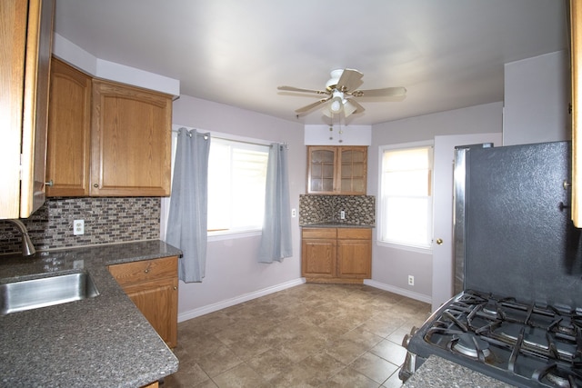 kitchen featuring ceiling fan, freestanding refrigerator, gas stove, a sink, and baseboards