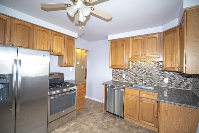 kitchen with tasteful backsplash, a sink, a ceiling fan, dark stone counters, and stainless steel appliances