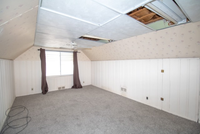 additional living space with carpet flooring, visible vents, wallpapered walls, and lofted ceiling