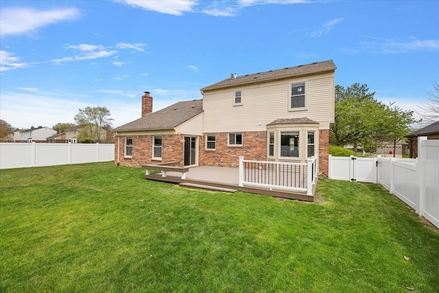 back of house featuring a chimney, a fenced backyard, a wooden deck, and a lawn