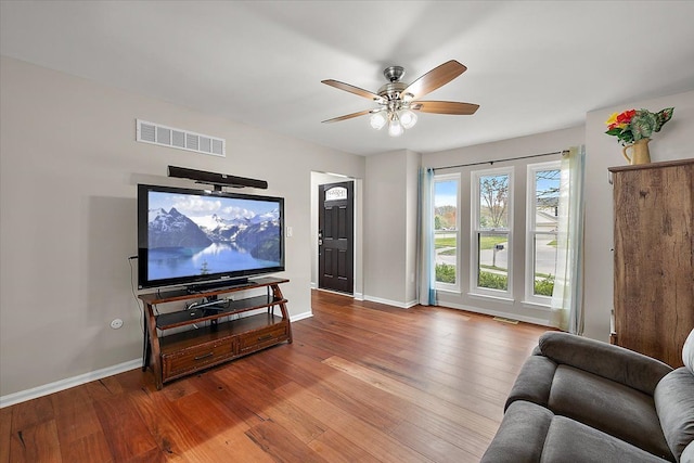 living room featuring baseboards, visible vents, hardwood / wood-style flooring, and ceiling fan
