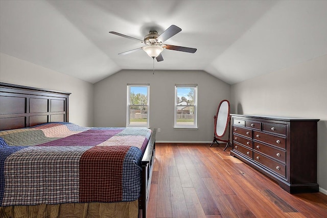 bedroom with a ceiling fan, vaulted ceiling, wood finished floors, and baseboards