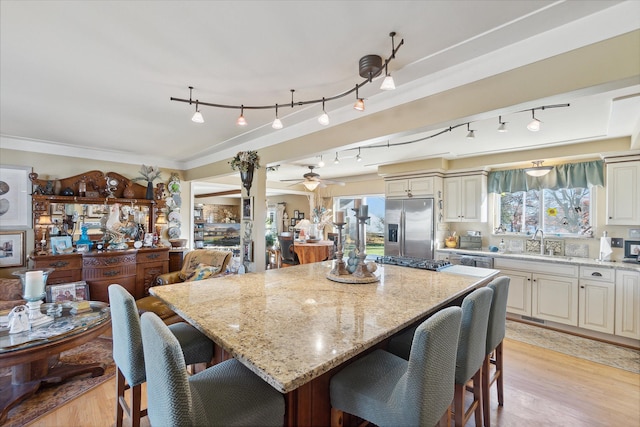 dining space with light wood-type flooring, ornamental molding, and a ceiling fan