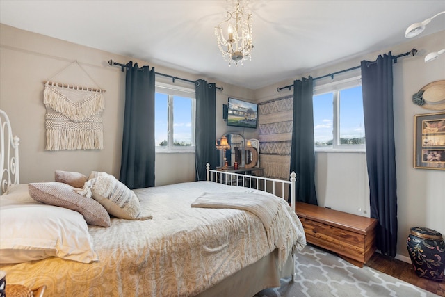 bedroom with multiple windows, a chandelier, and wood finished floors