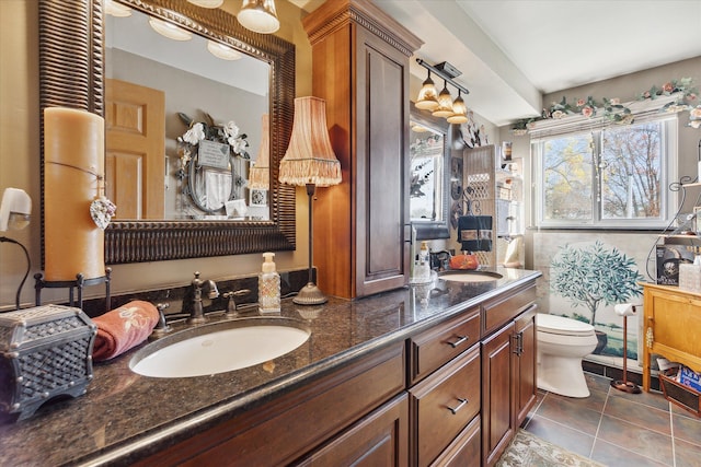 bathroom featuring a sink, tile patterned floors, toilet, and double vanity