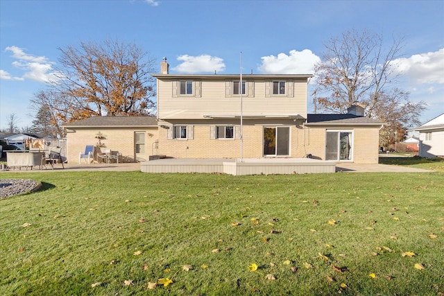 back of property with a patio area, brick siding, a chimney, and a lawn