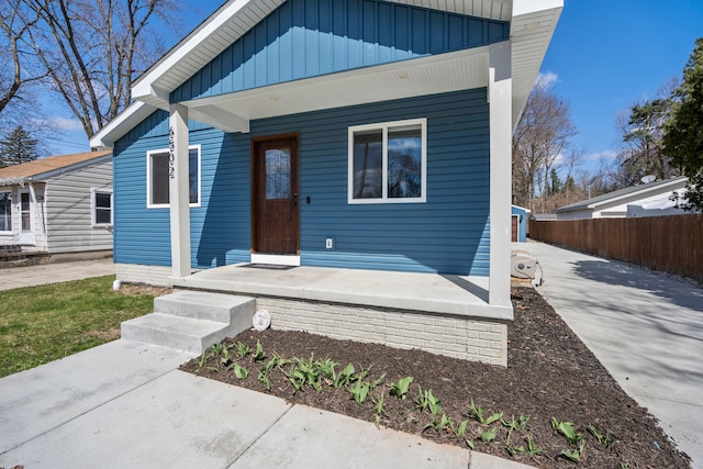 bungalow featuring board and batten siding, a porch, and fence
