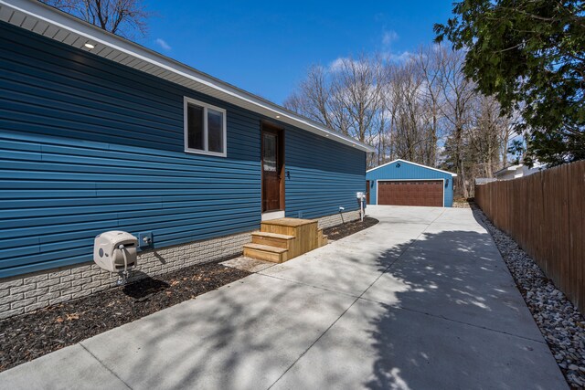 view of side of property featuring an outbuilding, a detached garage, and fence