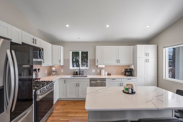kitchen with a sink, a kitchen bar, white cabinetry, stainless steel appliances, and lofted ceiling