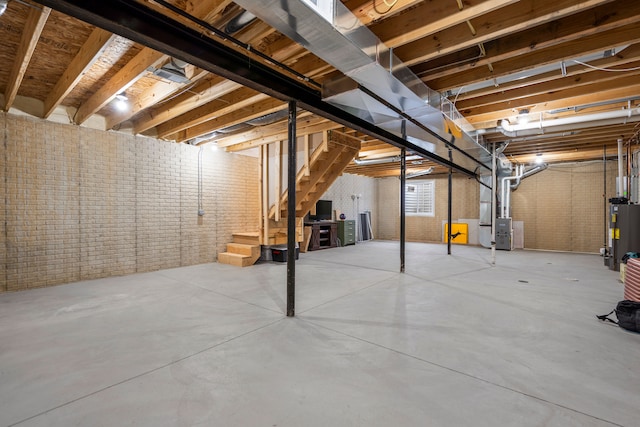 unfinished basement with brick wall, stairway, water heater, and heating unit