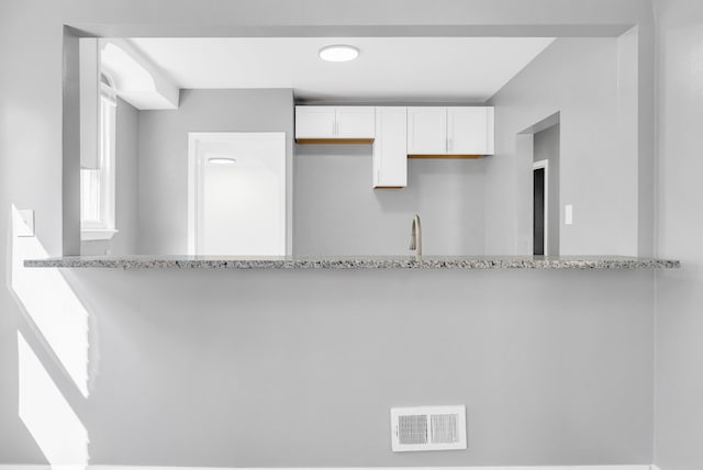 13955 Prevost St, Detroit, MI 48227 - kitchen featuring visible vents, white cabinetry, a peninsula, and light stone countertops
