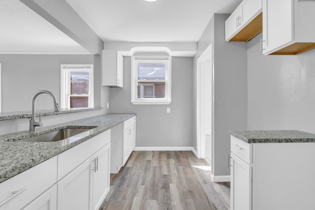 13955 Prevost St, Detroit, MI 48227 - kitchen featuring light stone countertops, white cabinetry, a sink, light wood finished floors, and baseboards